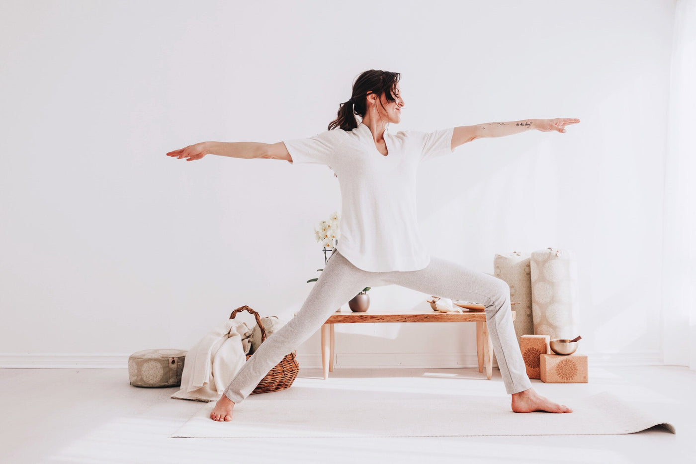 Warrior two pose in the ecru Harmony Tunic in a sunlit studio